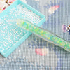 A glow-in-the-dark diamond painting pen with a translucent green body and colorful tips rests on a light blue tray.