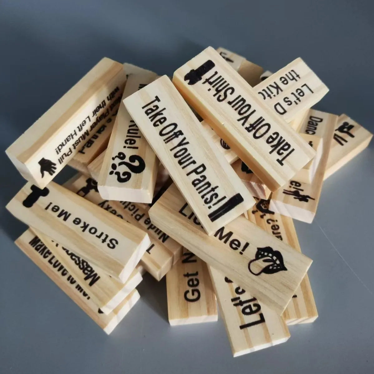 A pile of wooden stacking blocks with various phrases like Take Off Your Shirt and Let's Dance