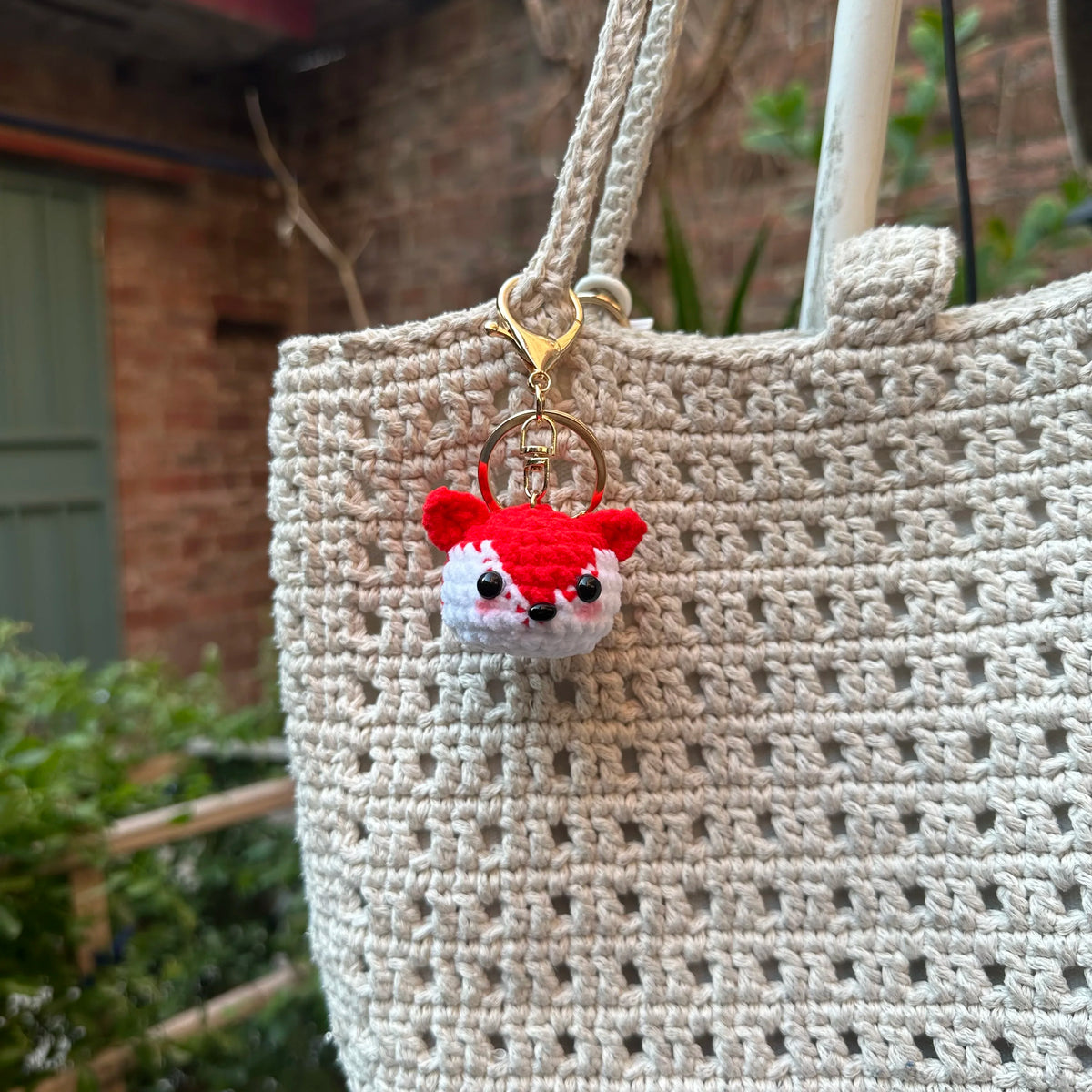 A handcrafted crochet animal keychain featuring a small red and white rabbit head attached to a gold-colored ring.