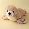 A light brown seal plush toy with a white snout and dark eyes resting on a beige surface.