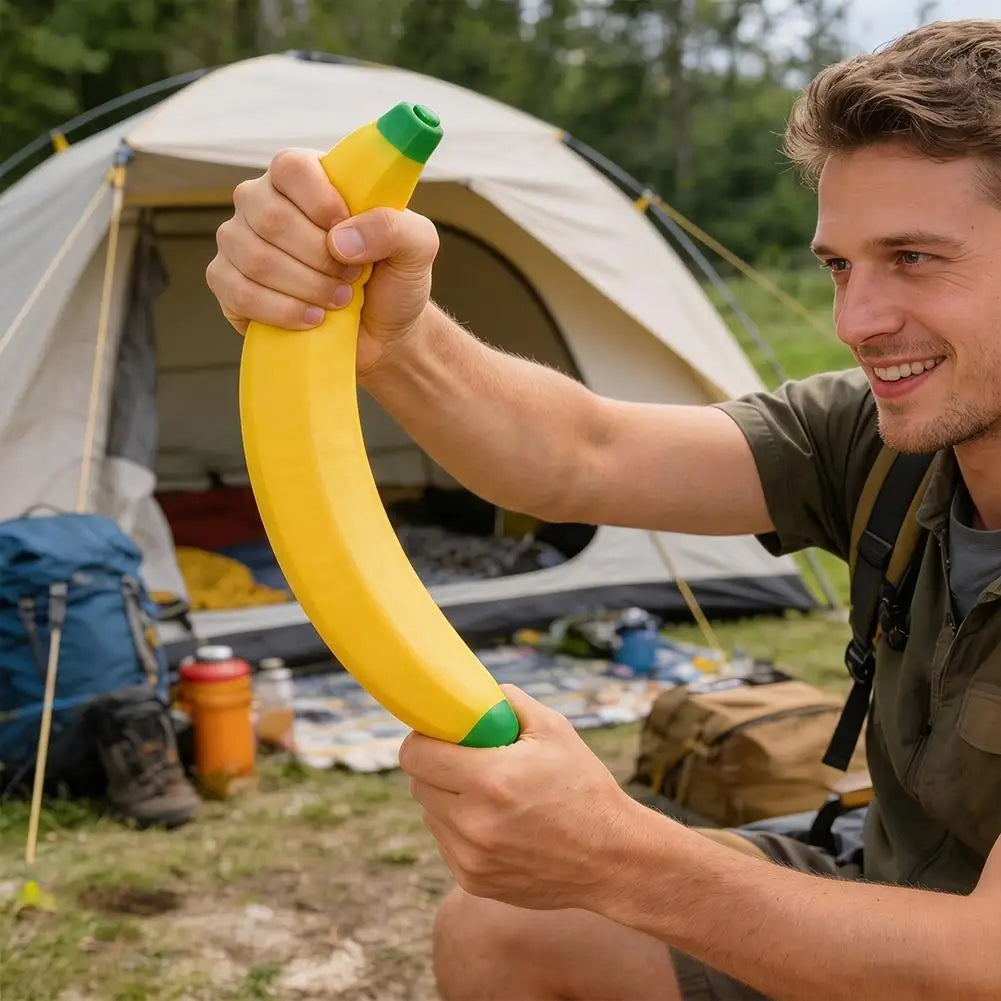 A man holds a yellow banana squishy stress relief toy outdoors near a tent.