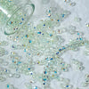 A pile of multicolor aurora cut glass beads scattered on a white surface.