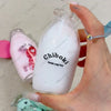 A hand holds a white bottle labeled Chiboki drink cup toy and a green squishy fidget toy.
