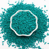 A pile of teal polymer clay slice sprinkles for slime and DIY crafts, with a white dish in the center.
