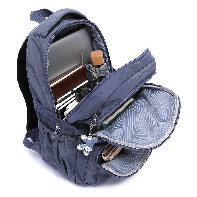 Un sac à dos de voyage bleu foncé et durable, ouvert pour montrer les compartiments pour fournitures scolaires et effets pers