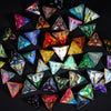 A collection of seven polyhedral resin dice in various colors and shapes arranged on a dark surface.