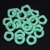 A pile of light green, smooth, ring-shaped acrylic spacer beads for jewelry making.