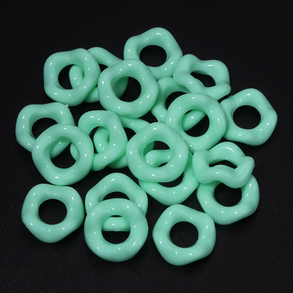 A pile of light green, smooth, ring-shaped acrylic spacer beads for jewelry making.