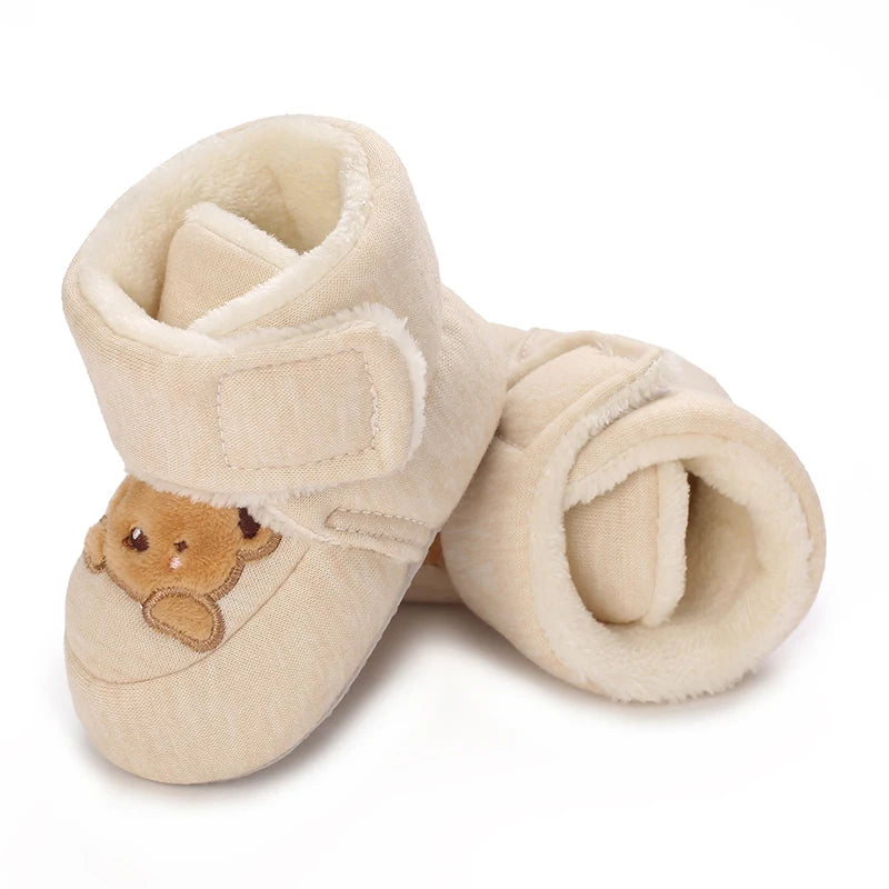 A pair of light beige baby winter cartoon boots with a soft, fuzzy texture and a non-slip sole.