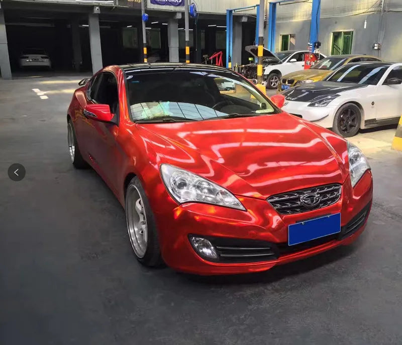 A red Toyota Camry is parked inside a garage with other cars visible.