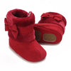 A pair of red faux fur baby first walker shoes with bow details.