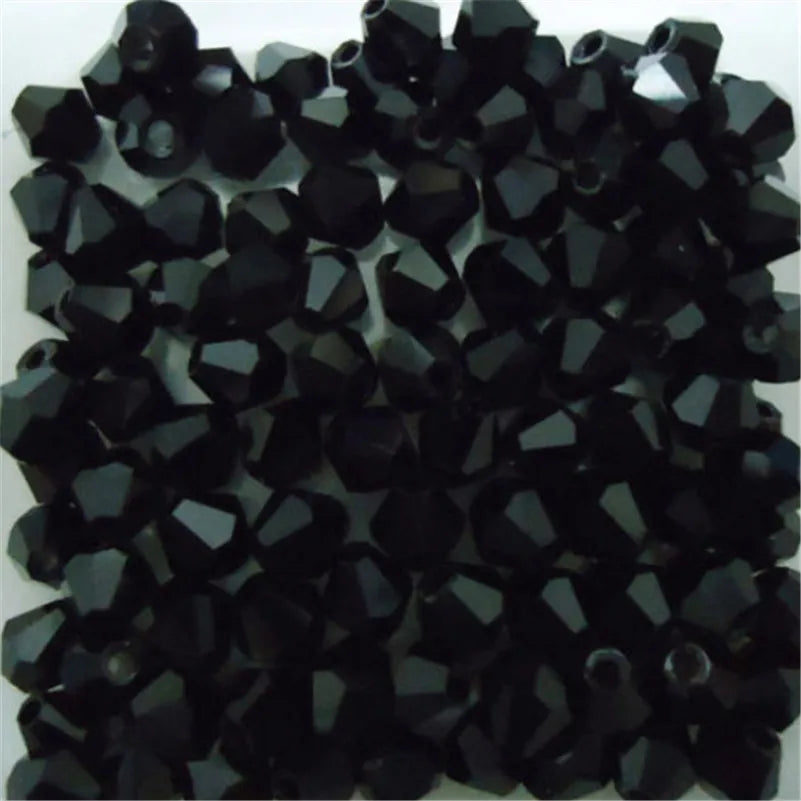 A pile of faceted black glass bicone beads for jewelry making.