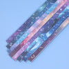A collection of 27 assorted colored origami star strips with celestial designs laid out diagonally.