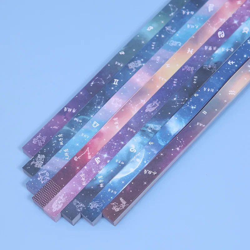 A collection of 27 assorted colored origami star strips with celestial designs laid out diagonally.