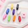 A collection of colorful acrylic letter beads in various shades and shapes arranged on a white tray.