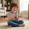 A young boy is playing with a white wind-up bouncing chick toy on a light rug.