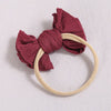 A maroon fabric bow headband with a light beige elastic band, shown against a white background.