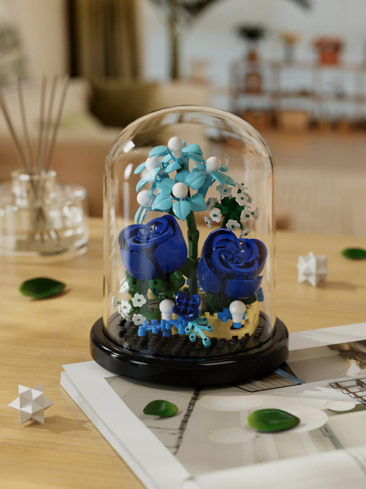 A glass dome display of a blue eternal rose flower kit featuring blue and white blossoms on a dark base.