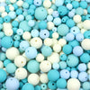 A close-up view of a pile of matte acrylic beads in various shades of light blue, white, and pale blue.