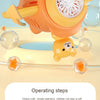 An orange bear-shaped automatic bubble gun is shown firing bubbles onto a surface.
