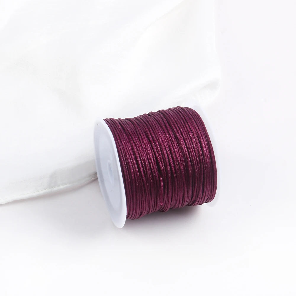 A roll of deep magenta cotton nylon macrame cord for jewelry making and crafts.