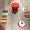 A red container with a lid and a colorful plastic board game setup featuring colored beads.