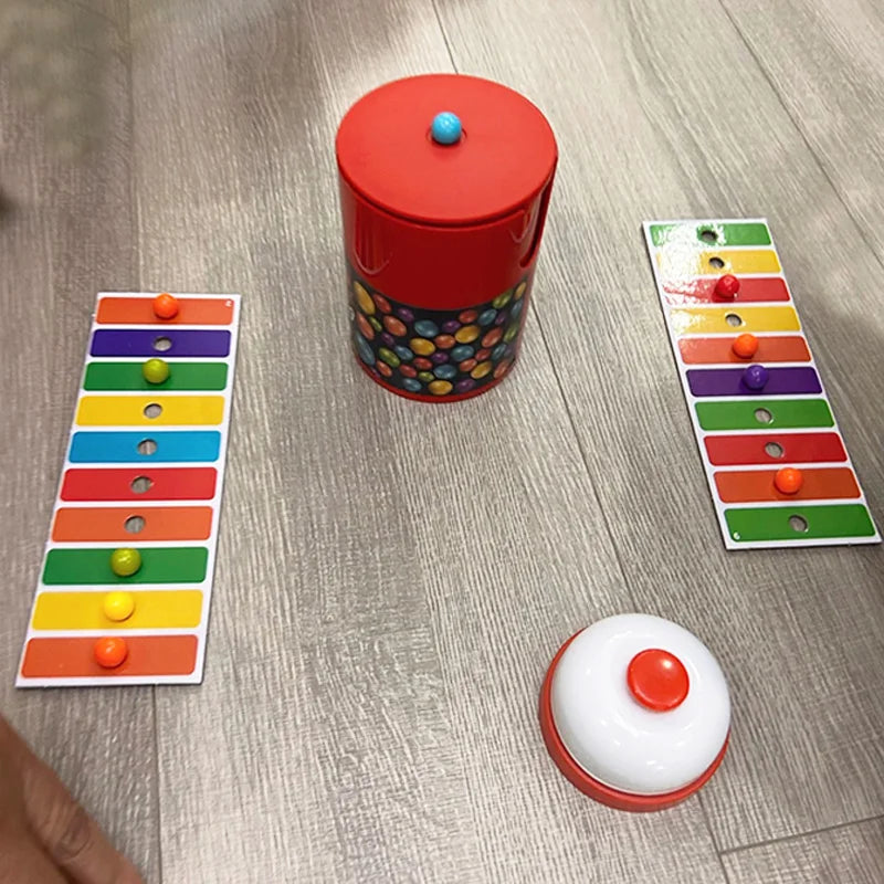 A red container with a lid and a colorful plastic board game setup featuring colored beads.