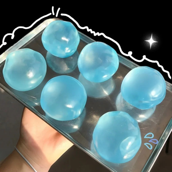 Une main tient un contenant transparent rempli de jouets anti-stress en huile de coco bleu clair.