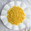 A white plate filled with yellow plastic bead filler for DIY squishy toys and crafts