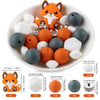 A bowl filled with various orange and gray silicone beads shaped like foxes, including round, flat, and ring-shaped pieces.