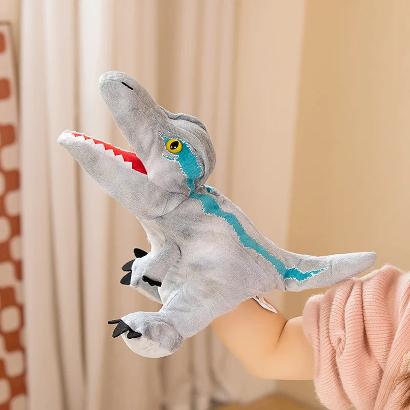 Marionnette en peluche d'un dinosaure gris avec des accents bleus tenue par une personne.
