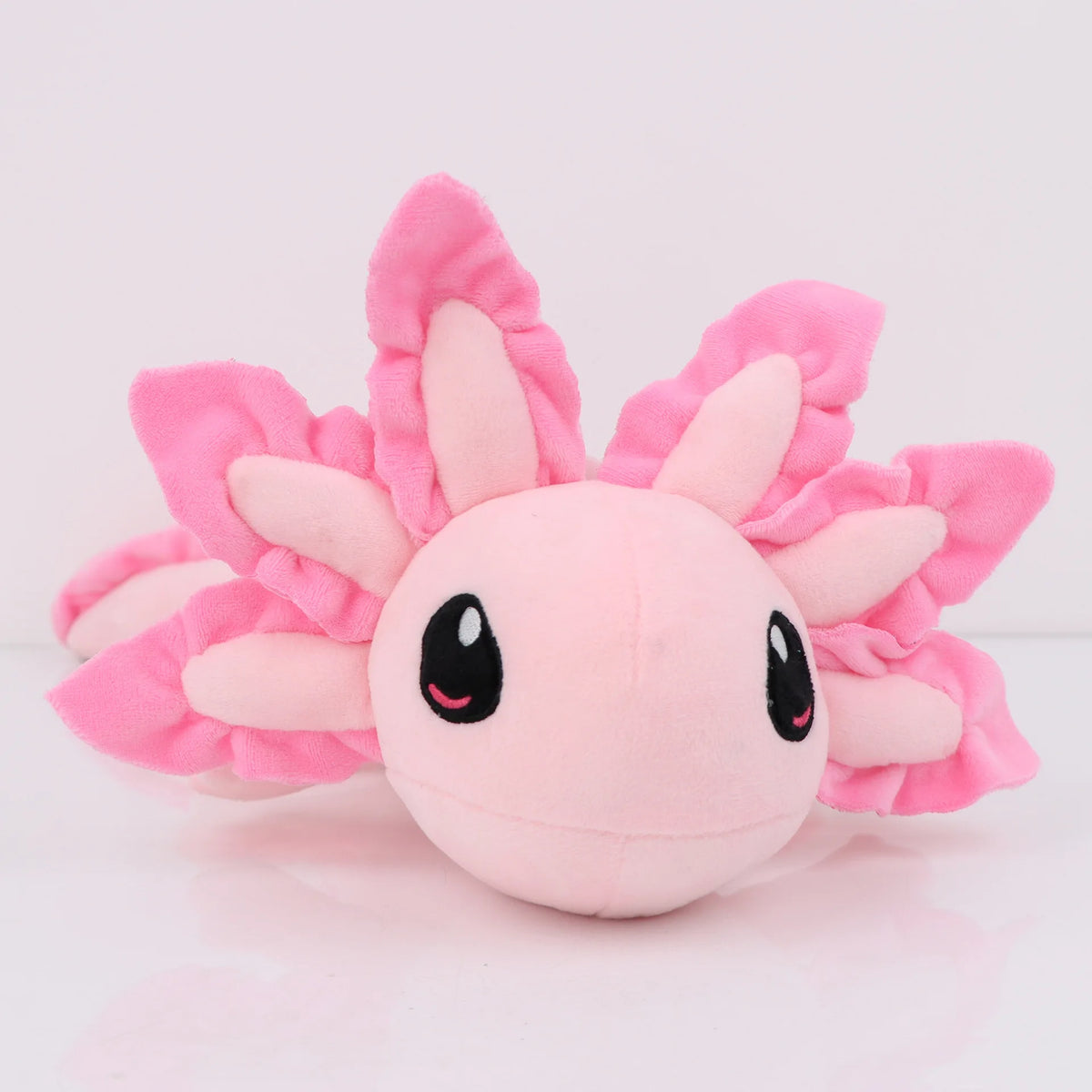 A pink kawaii axolotl plush toy with large pink petal-like ears and black eyes.