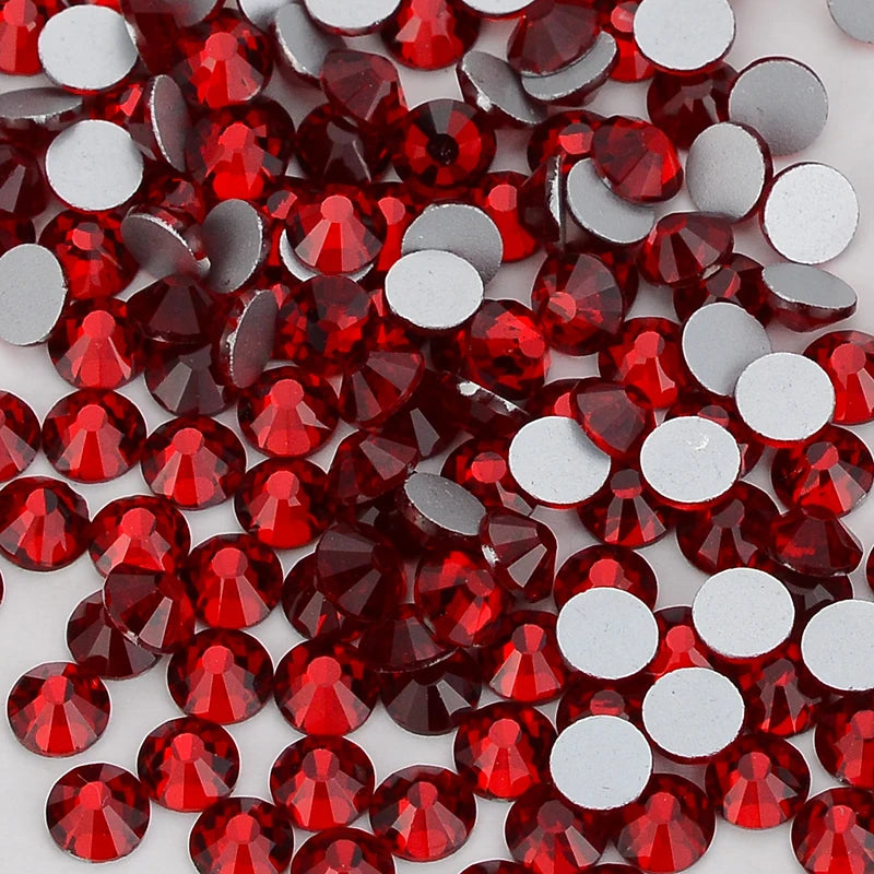 A close-up view of red and silver glass crystal flatback rhinestones scattered on a white background.