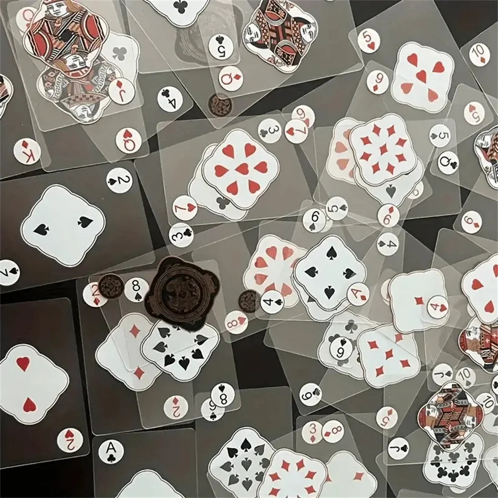 A collection of waterproof transparent playing cards featuring various suits and cards scattered on a dark surface.