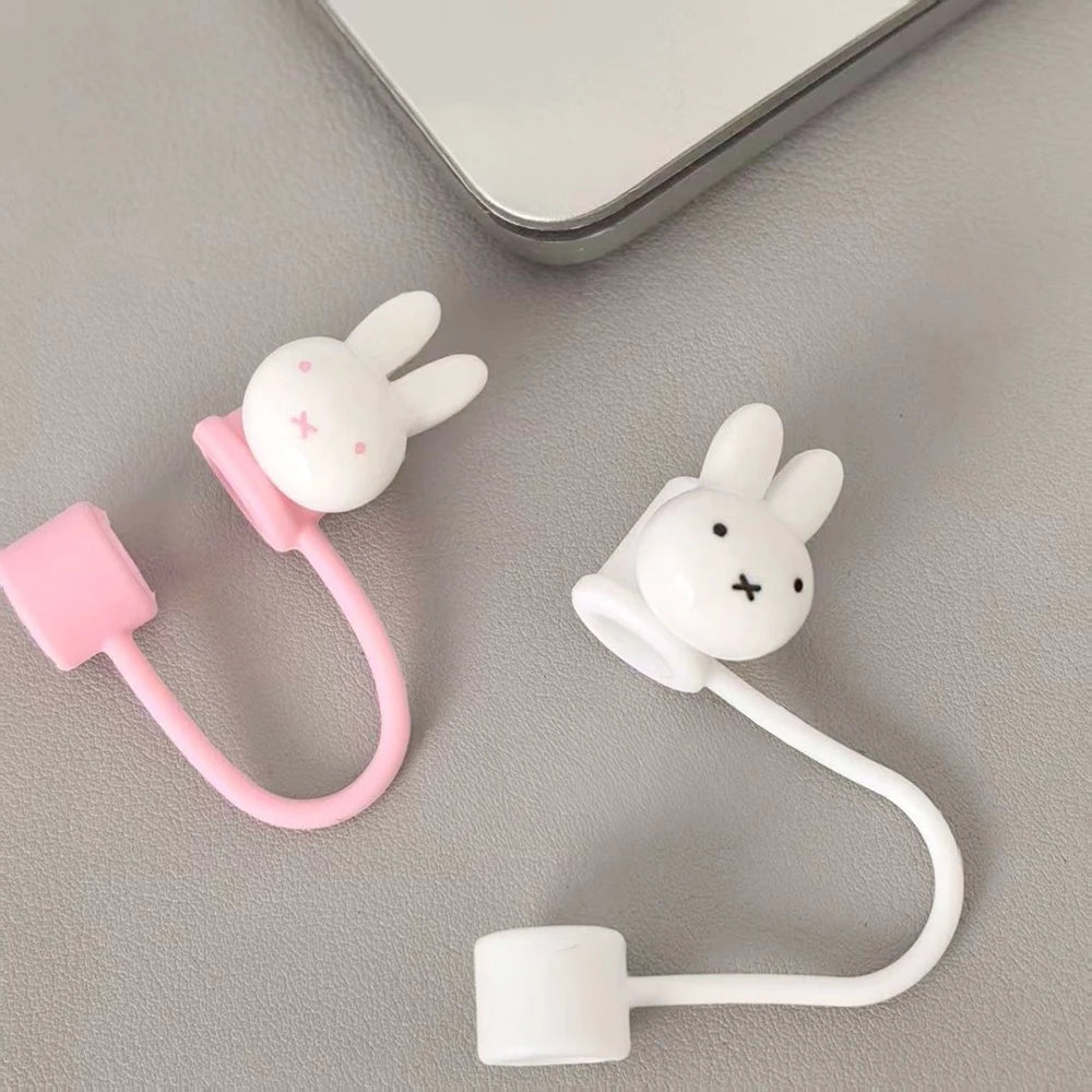 A white Miffy straw topper with a pink loop and a white stopper is shown on a gray surface.