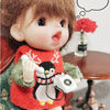 A small doll wearing a red sweater with an arctic theme is holding a white rotary telephone miniature.