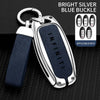 A silver blue buckle key case cover with a dark blue strap and metal keyring, shown on a black textured surface.