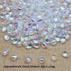 Clear iridescent water drop glass beads scattered on a beige surface