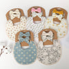 A set of three baby flower bibs and headbands in various floral patterns and pink, yellow, and gray colors.