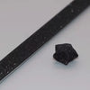 A close-up view of black glitter origami star paper strips lying on a white surface.