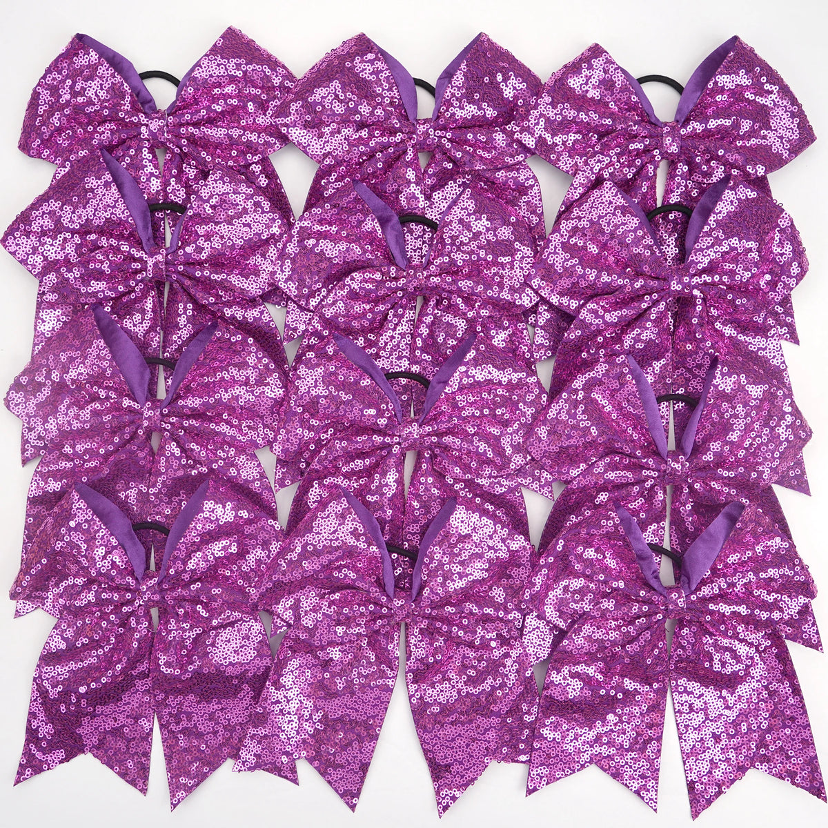 A pack of twelve purple glitter sequin pigtail bows for girls with elastic hair ties.