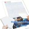 A hand holds a sheet of diamond painting cover paper featuring a blue and black seascape.