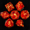 A collection of red resin dice with gold glitter accents arranged on a black surface.