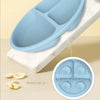 Un set d'alimentation en silicone bleu clair avec trois compartiments posé sur une surface en marbre blanc.