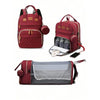 A maroon backpack diaper bag featuring a padded changing pad and an external USB port.
