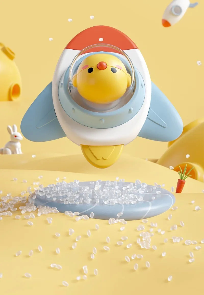 A yellow and white baby bath toy with a suction cup spinner is shown above scattered clear plastic beads on a yellow surface.