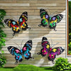 Set of four decorative iron butterflies in vibrant colors displayed on a wooden fence.