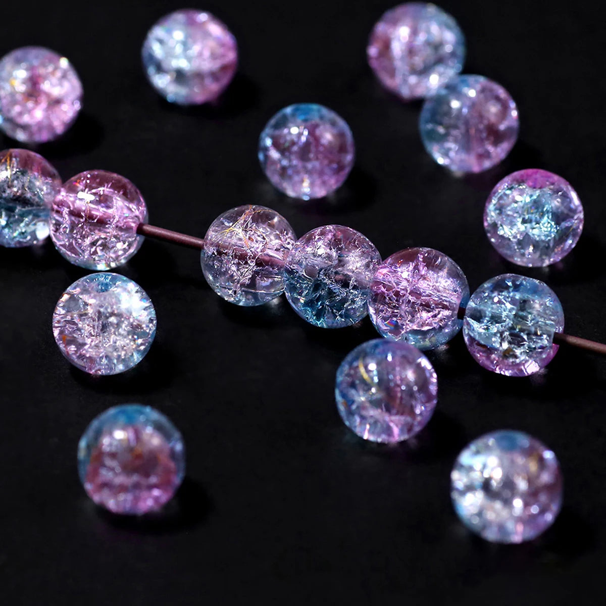 A string of gradient crystal glass beads with a golden crackle finish, showing various shades of purple and blue.
