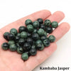 A handful of dark green Kambaba Jasper round beads for jewelry making resting on a hand.