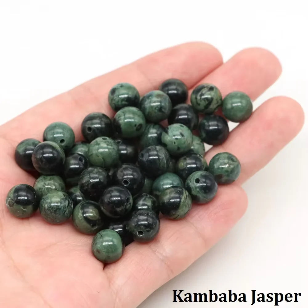 A handful of dark green Kambaba Jasper round beads for jewelry making resting on a hand.